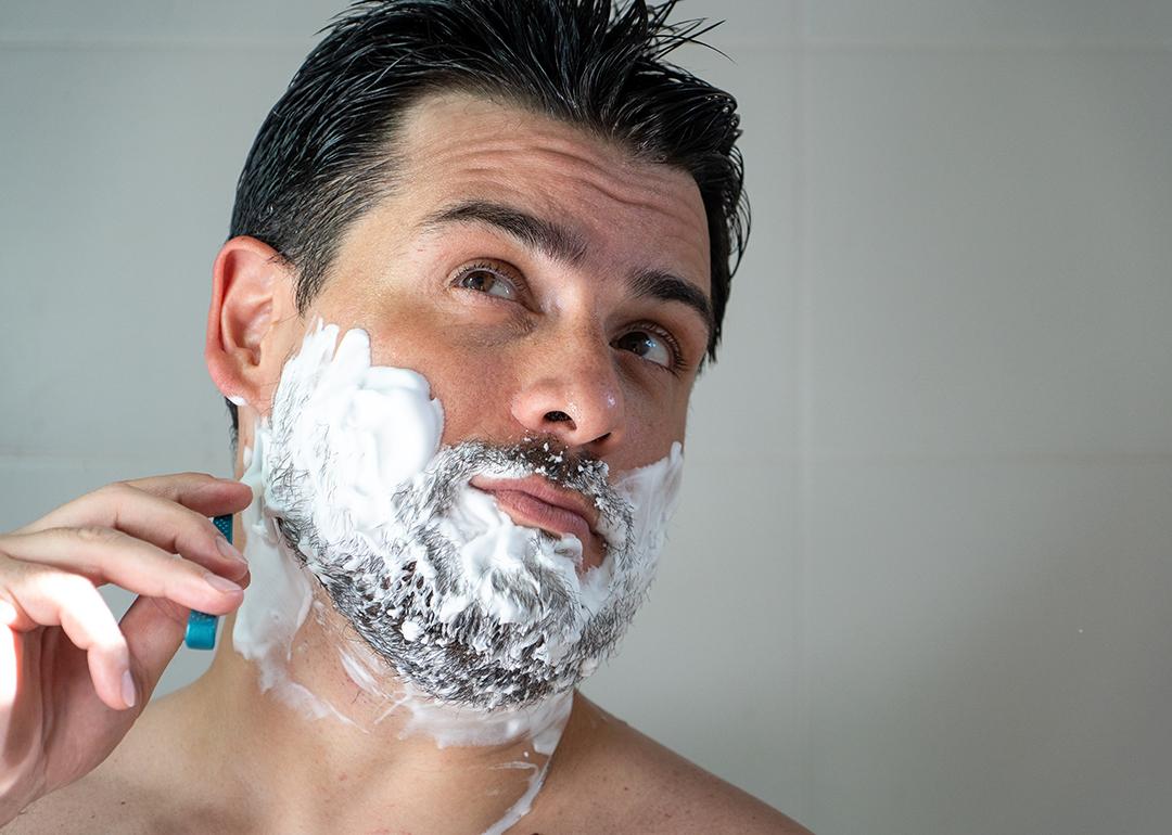 A young man shaving his beard.