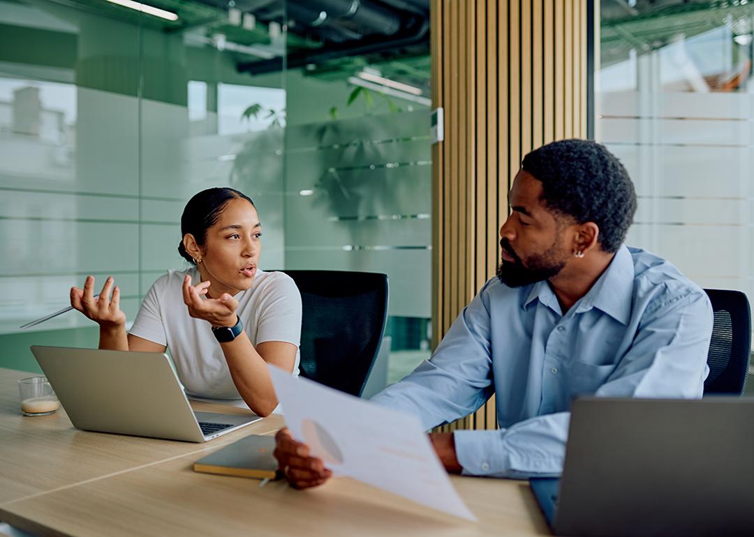 Two business colleagues engaged in discussion in a boardroom.