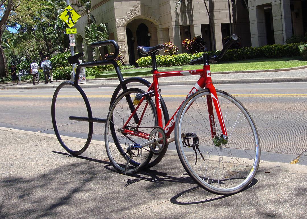 A red racing bicycle locked on a bicycle-shaped parking rack in Honolulu, Hawaii.