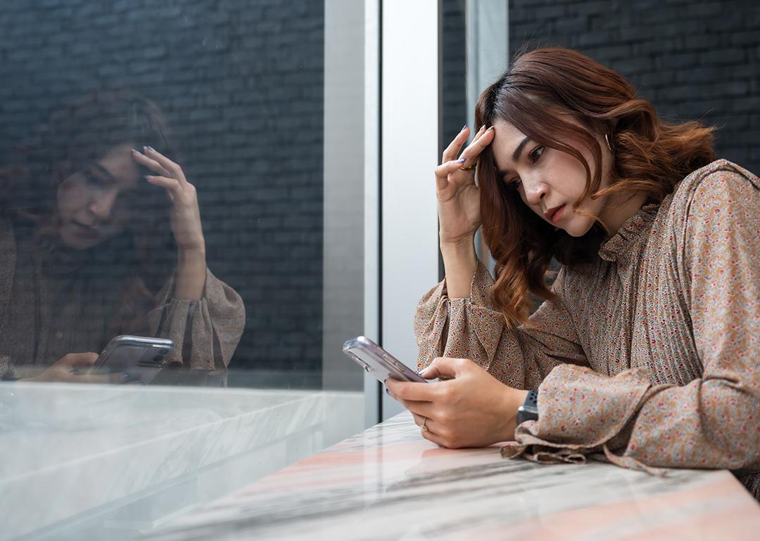 A person checking on her phone, while looking worried about something.