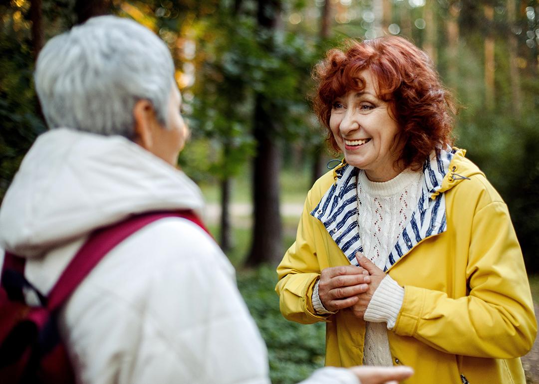 Two elderly female friends having a conversation out in the woods.