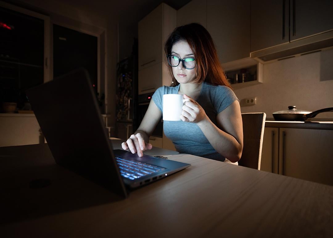 A young female professional working from a home's kitchen at night.