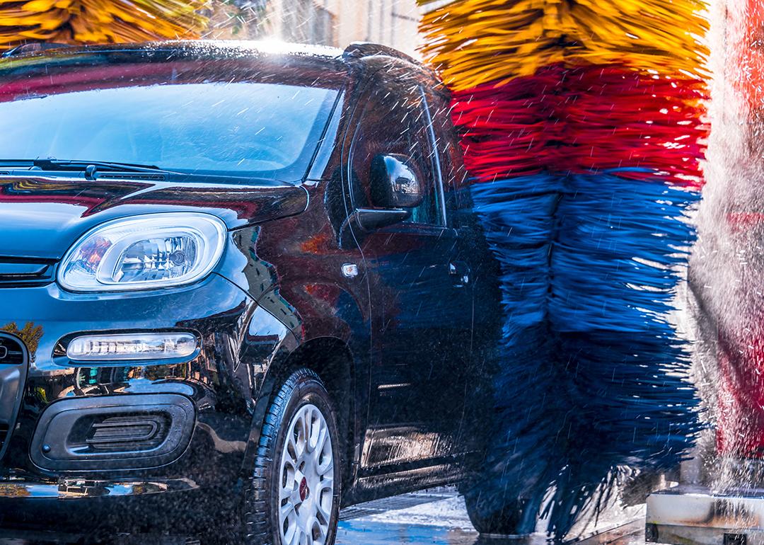 A car going through massive automated car wash brushes.