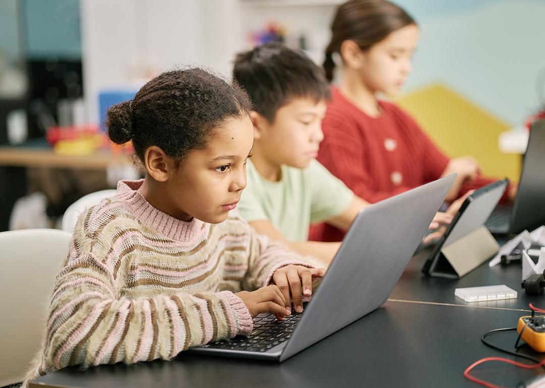 A group of children using laptops in a classroom.