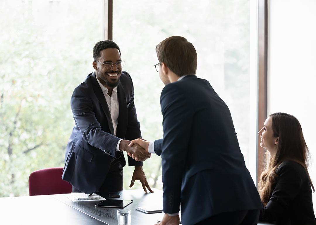 Business partners shaking hands after securing a sales deal in an office.