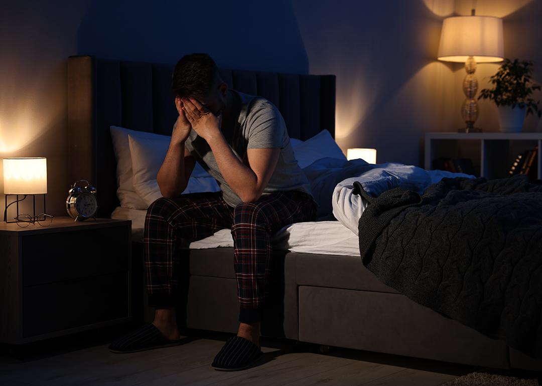 A man with his hands on his face after waking in the middle of the night.