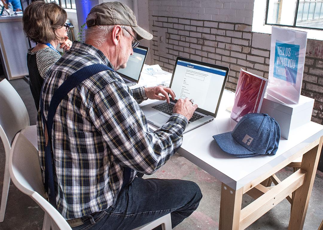 A senior man signing up for a Facebook account at a community boost event.