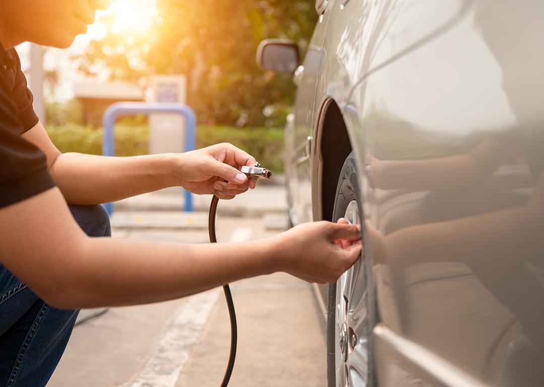 Man inflating car tires at a gas station.