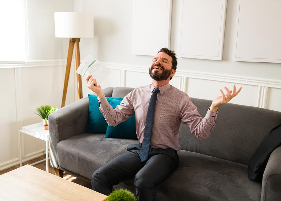 A businessman feeling free and happy while holding financial document.