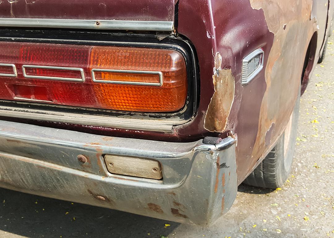A close-up shot of the back of an old rusty car. 