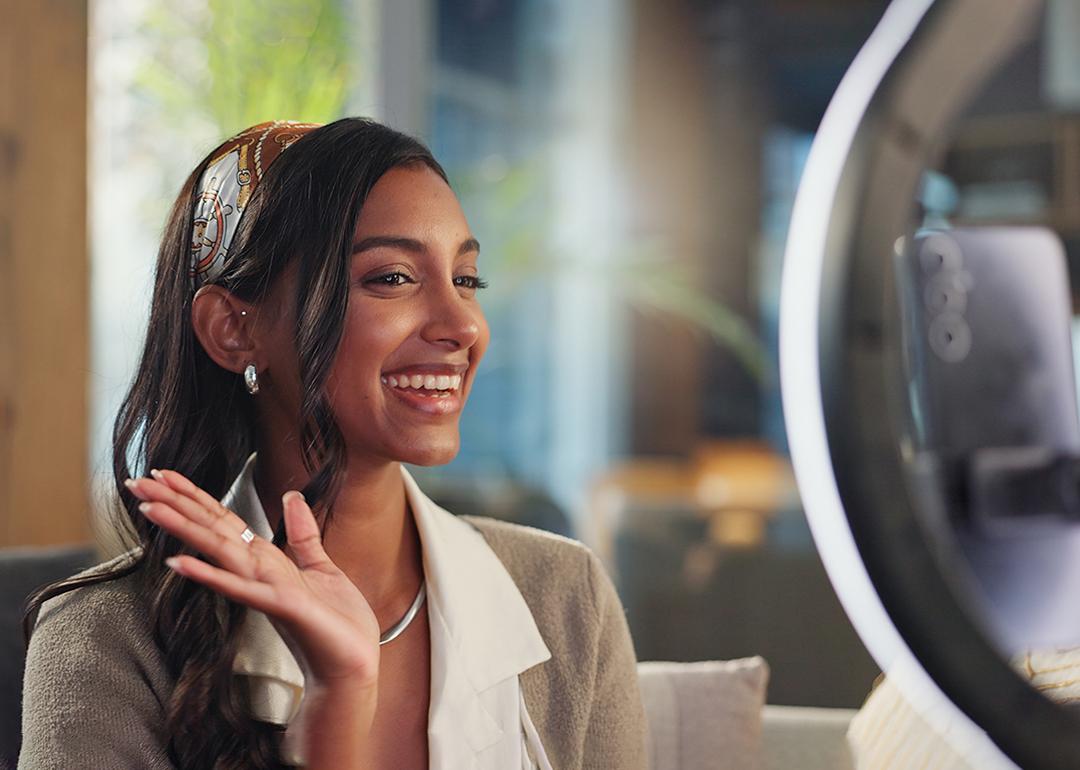 A young female influencer filming a vlog at home using a ring light and smartphone.