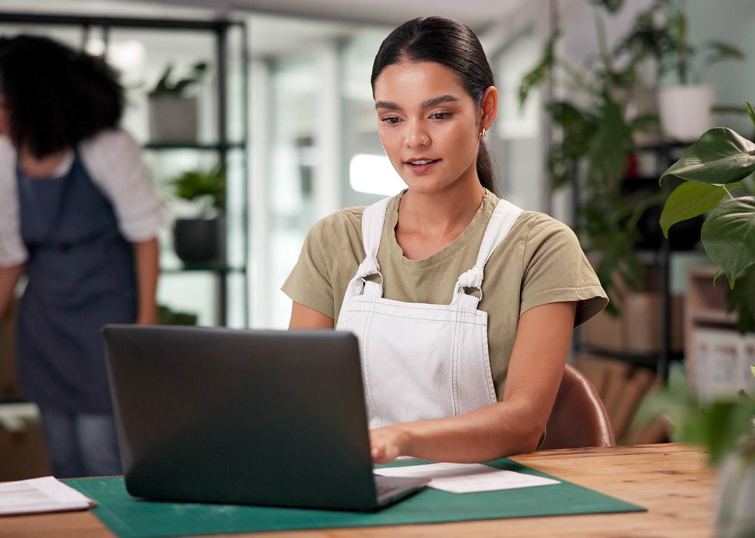 A female small flower business owner reviewing information on a laptop.