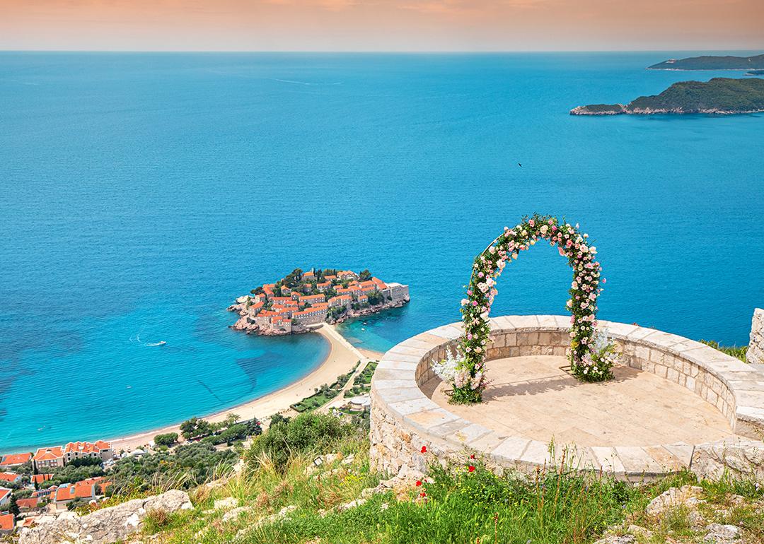 A romantic wedding ceremony at Montenegro Sveti Stefan viewpoint, with an arch adorned in flowers overlooking the Adriatic Sea.