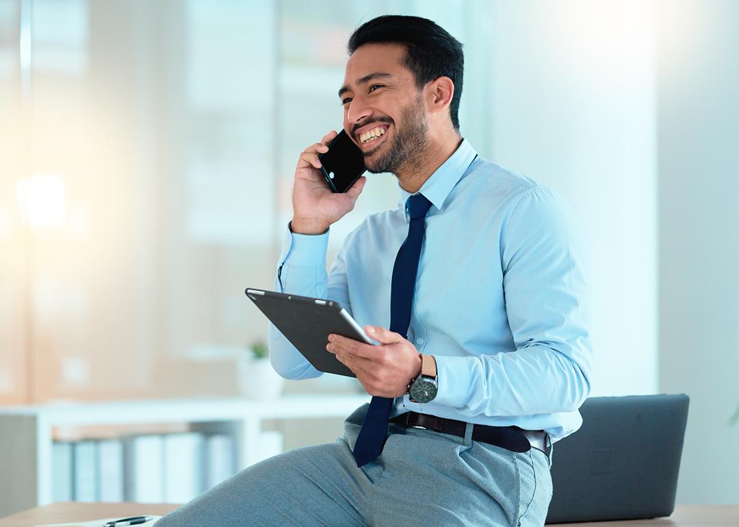 A happy businessman talking on the phone with a client.