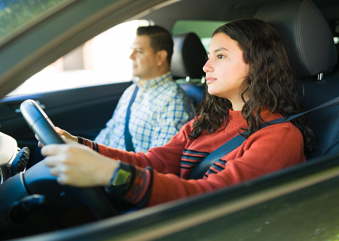 A teenage girl learning how to drive with her father.
