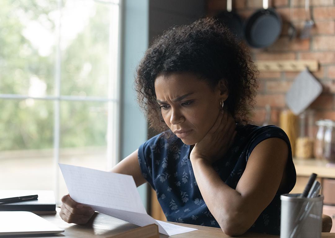 A frustrated young woman at home reading a letter with bad news.