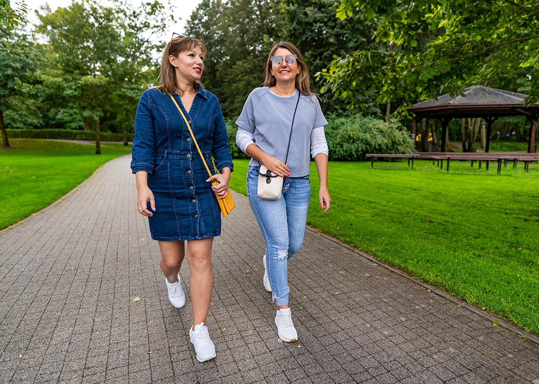 Two friends sharing stories while strolling in a city park. 