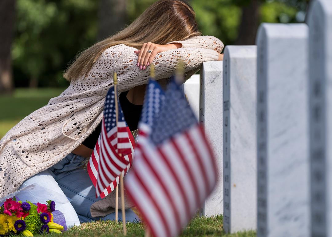 A young bridge grieving at a burial site of a family member in a military cemetery.