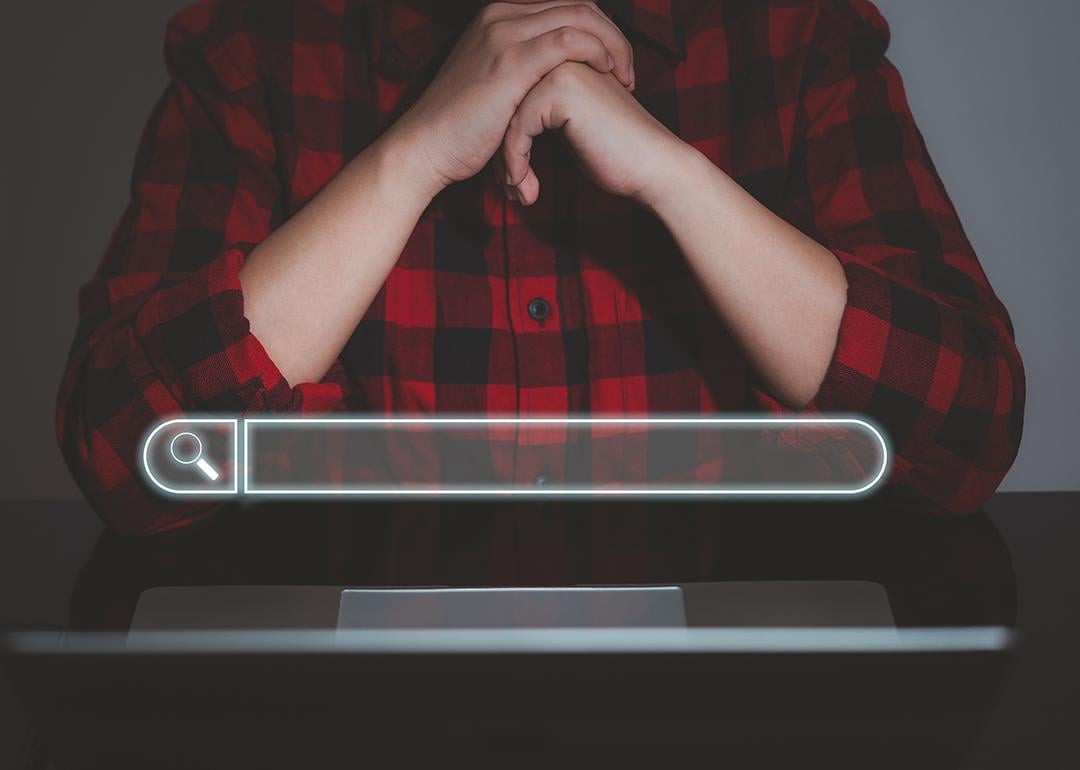 A floating search bar and a data analyst working on search engine concept from a laptop in the background.