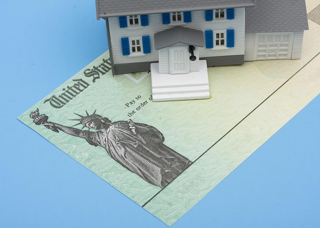 A miniature house placed over a U.S. tax refund check.