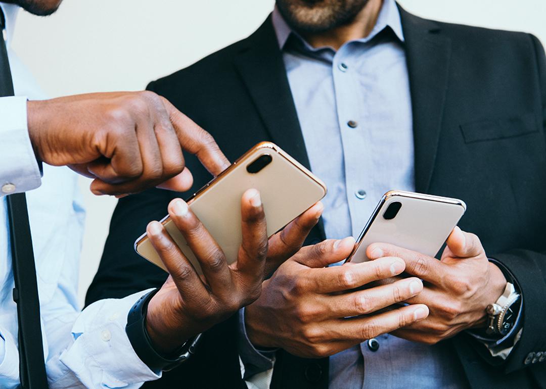 A business person showing an online post from his smartphone to a colleague. 