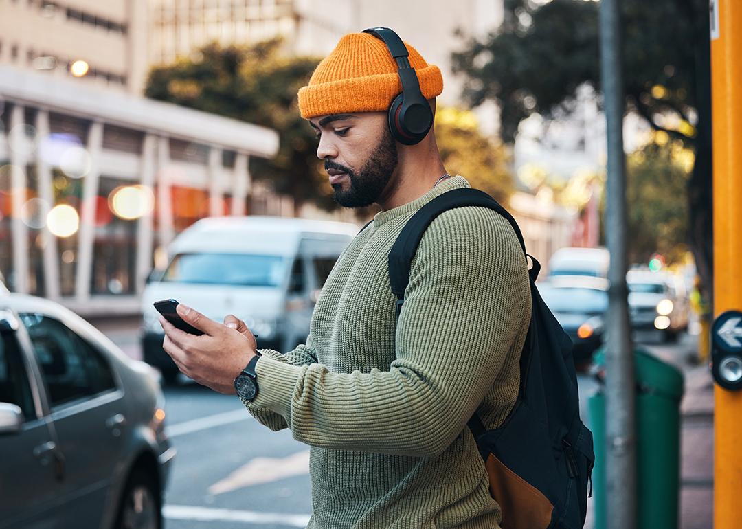 Man listening to music outdoors while about to cross a street.
