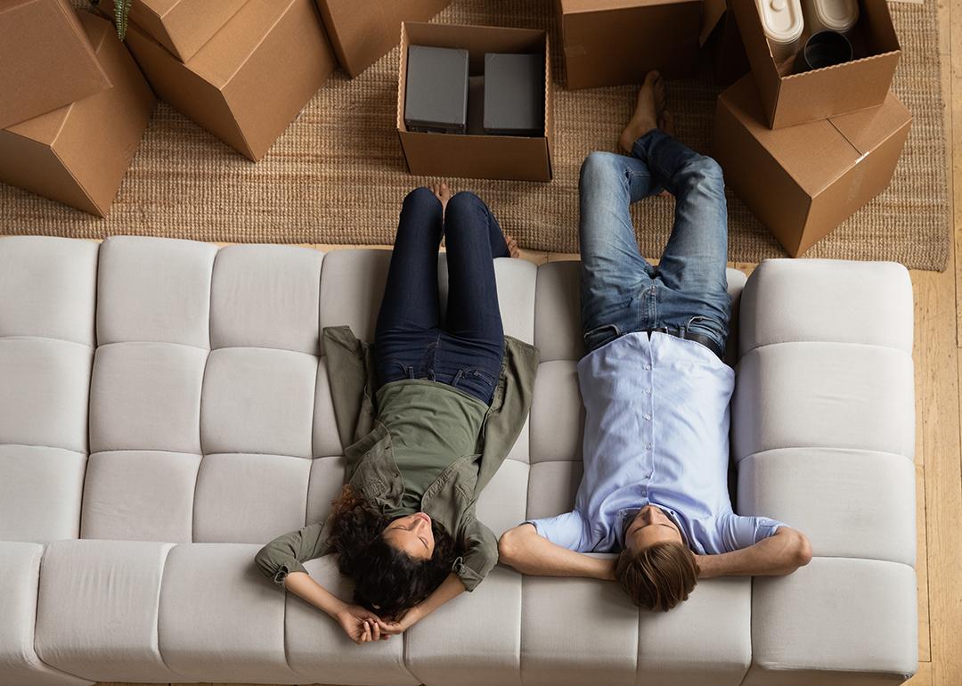 Overhead of a young couple taking a break on the sofa after moving to a new home.