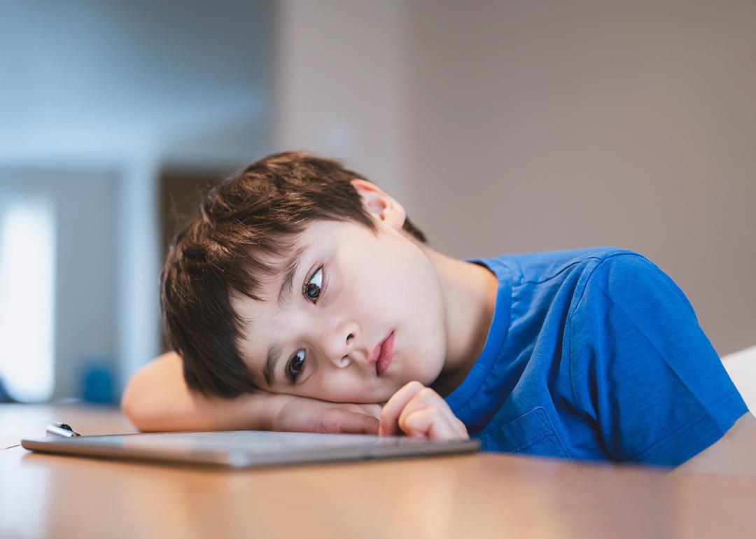 A bored young child staring at a tablet.