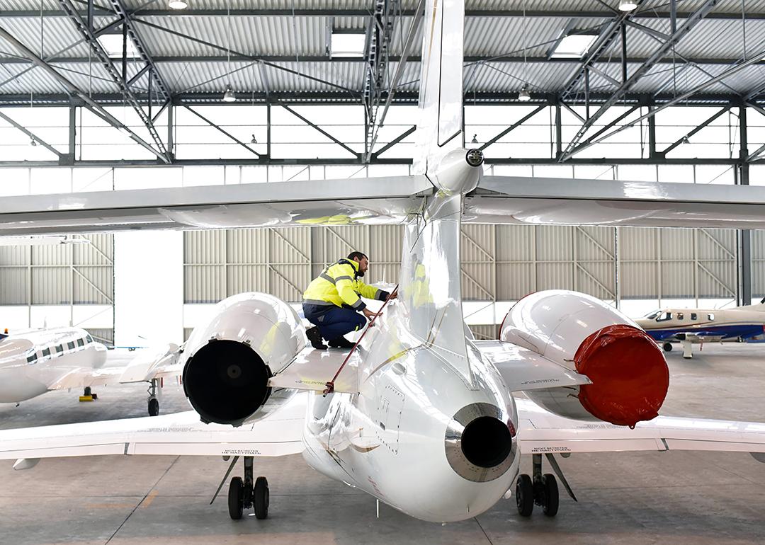 Airport workers check an aircraft for safety in a hangar.