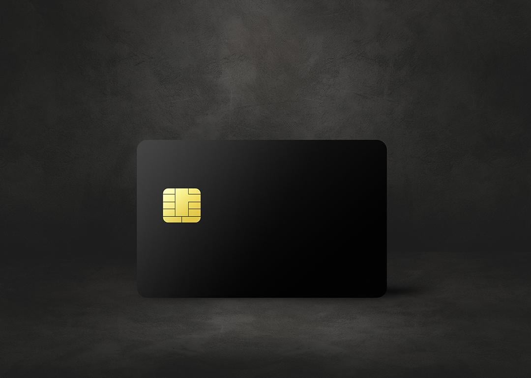 A black credit card in a dark concrete background.
