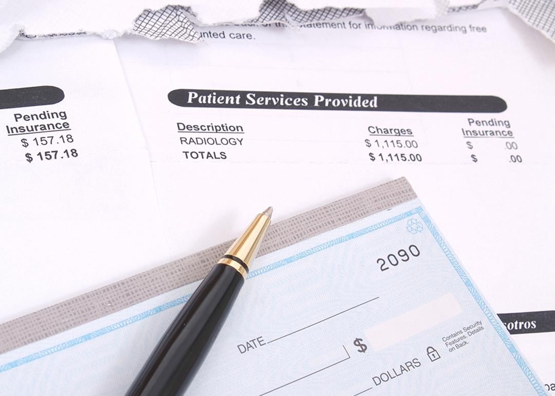 Medical bill statements and a check with a pen.