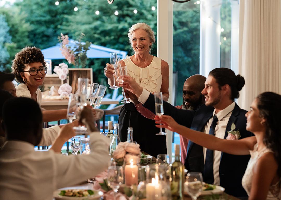 Guests raising glasses during a joyful toast from a wedding reception dinner.