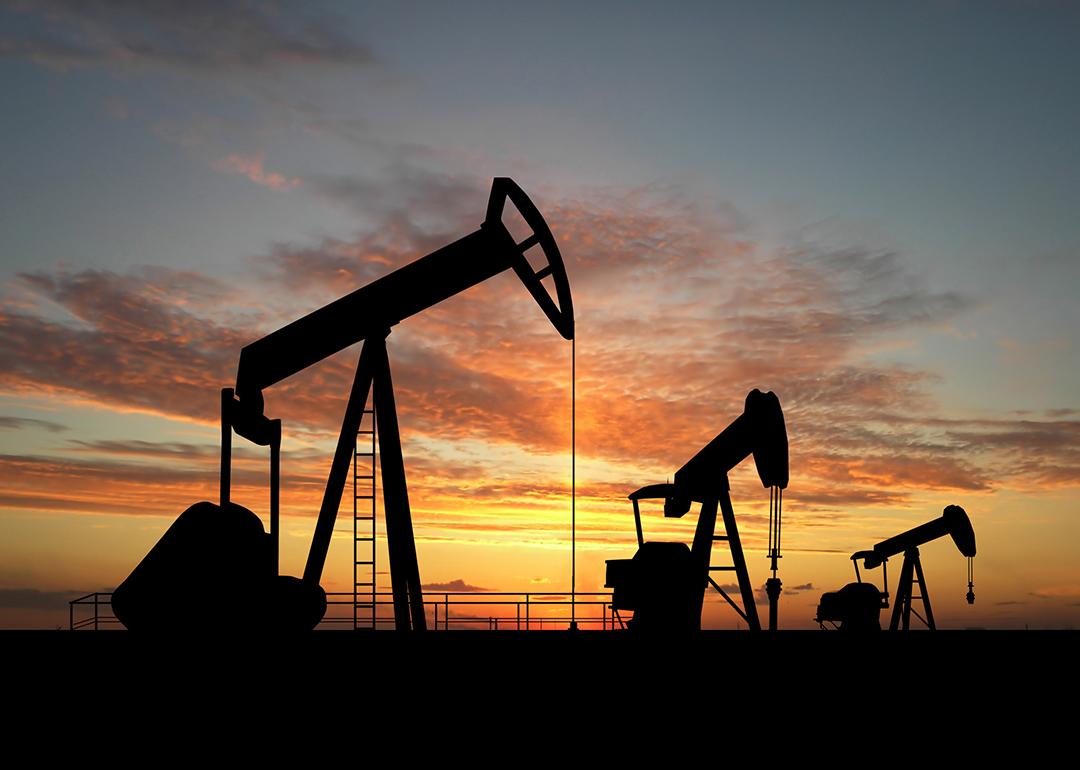 Silhouette of gas pumps machinery during sunset.