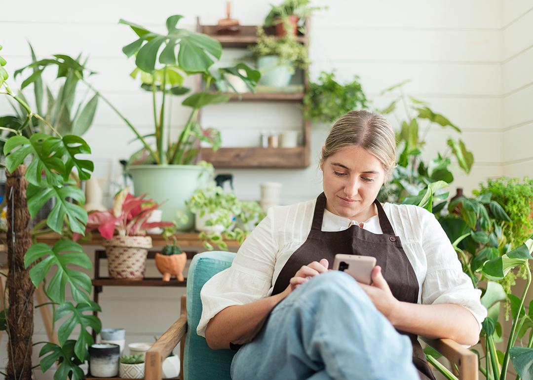 A female small garden business owner browsing information using a smartphone.