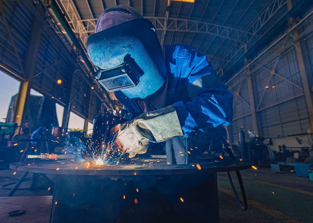 A person doing a mig welding on steels in a warehouse.