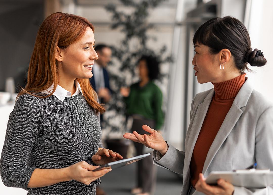 Two female professionals engaged in a positive discussion in an office.