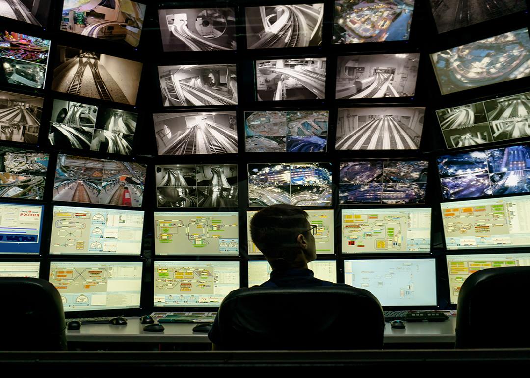 A security staff member overlooking a multiple display monitoring system.