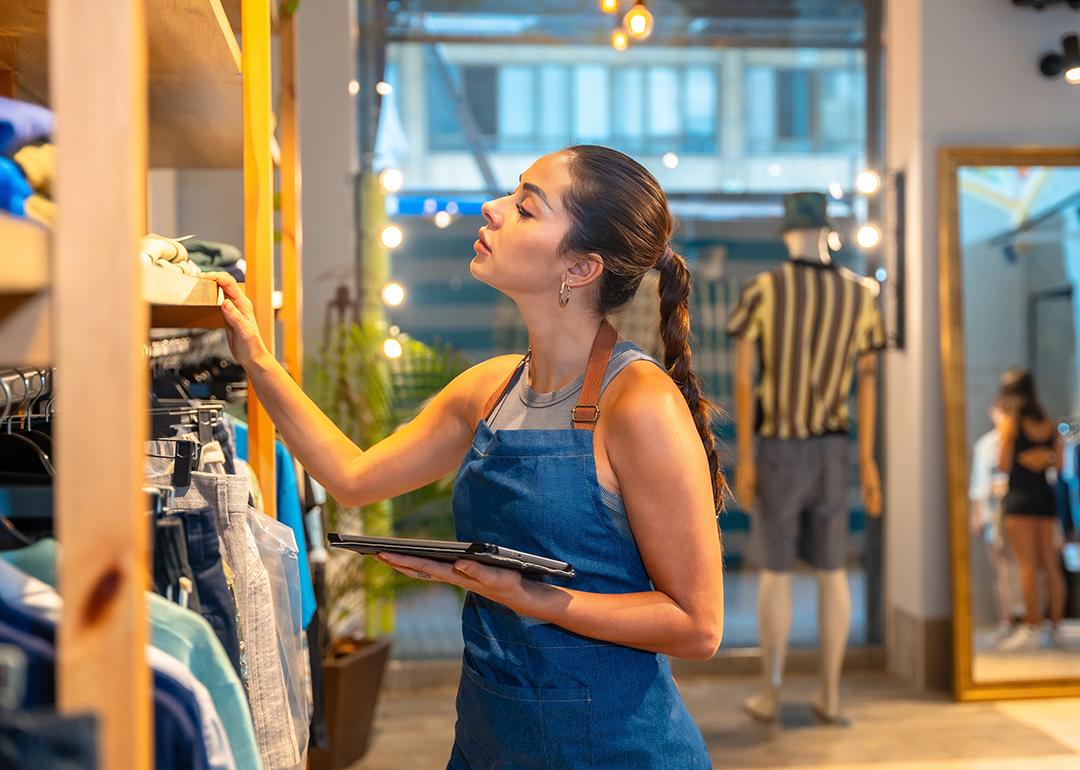 A young female store assistant checking clothing inventory.