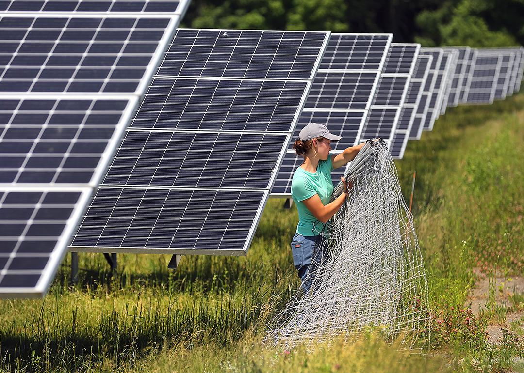 A worker organize fencing materials along solar panels at the Fitchburg Renewables solar farm in Massachusetts.