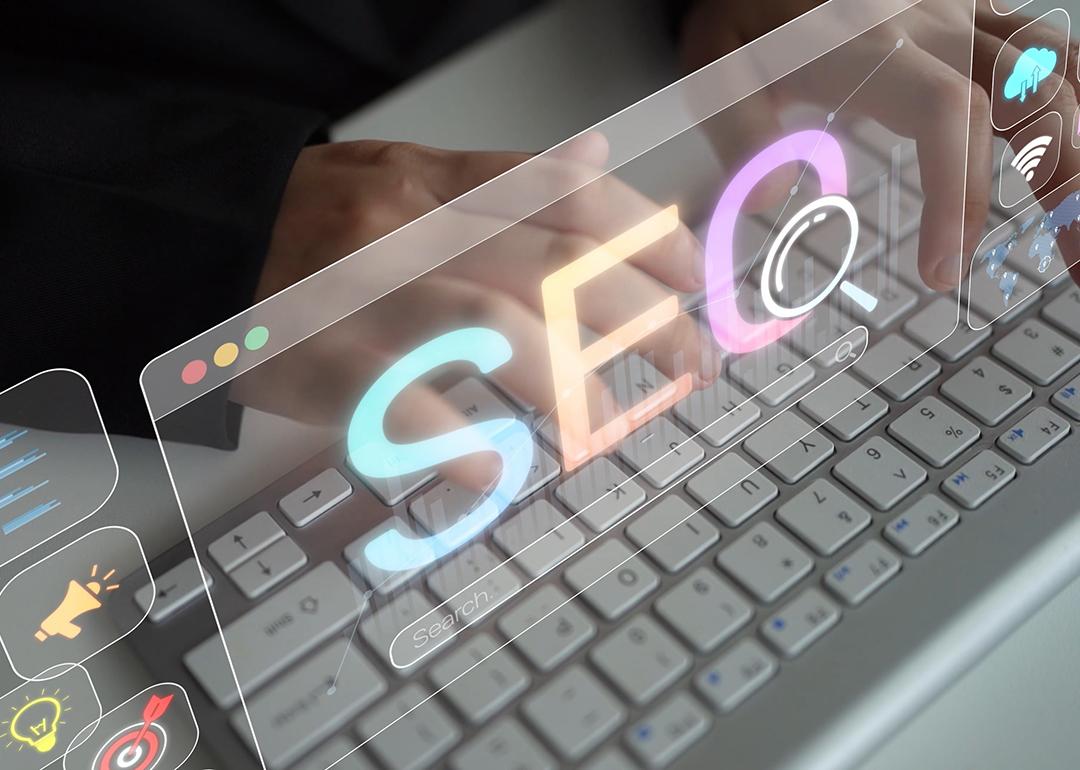 Holographic SEO concepts over a focused person using a keyboard.