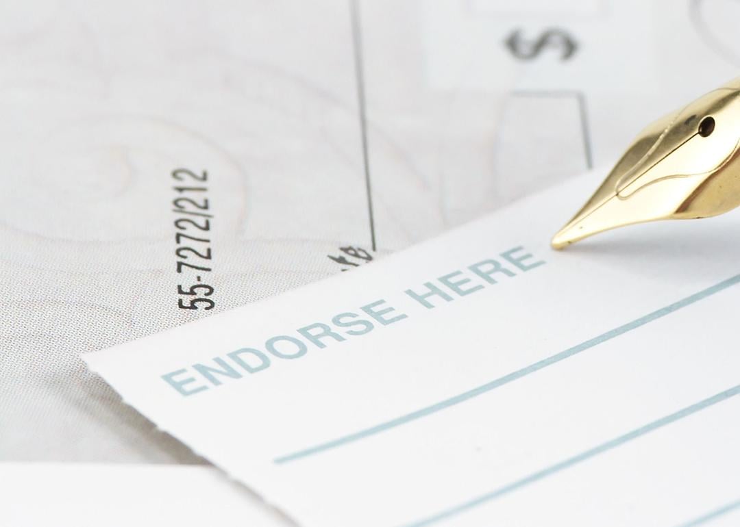 A pen signing an endorsement note to a check.