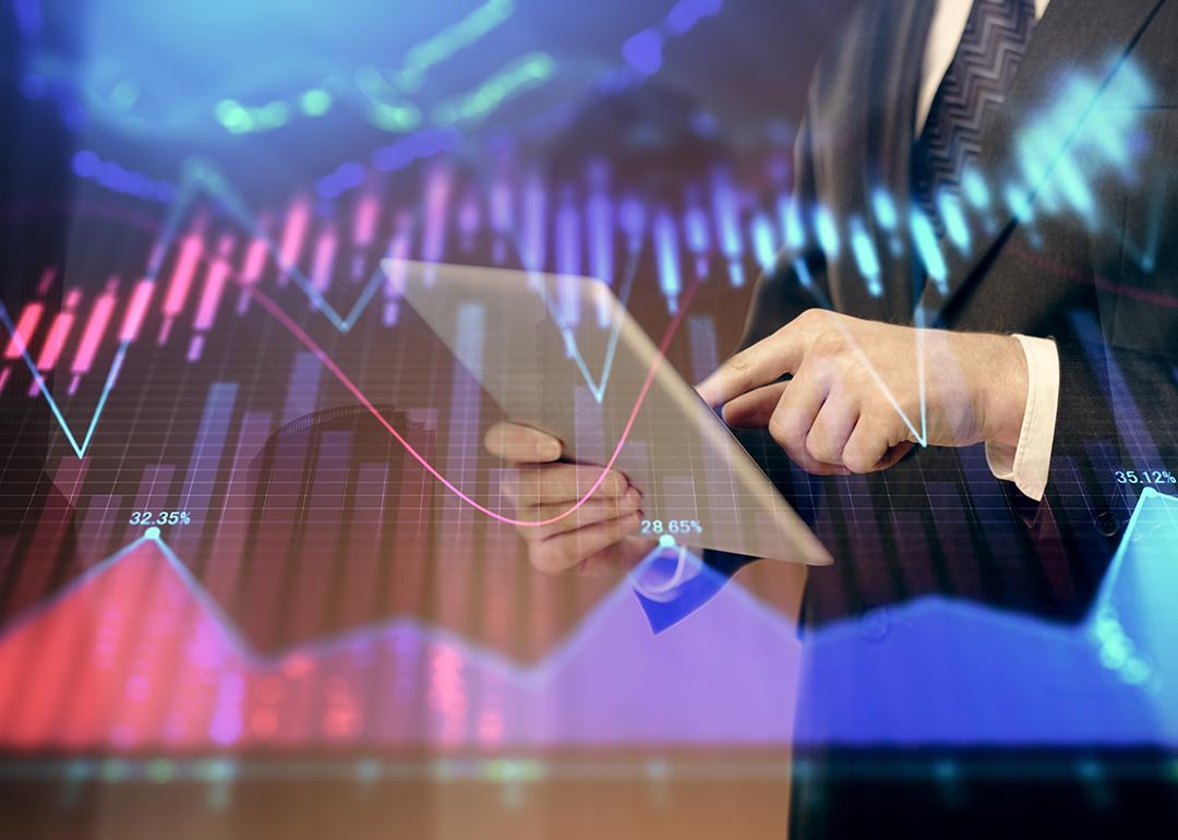 A financial marketer using a tablet with an overlay of forex graphs.