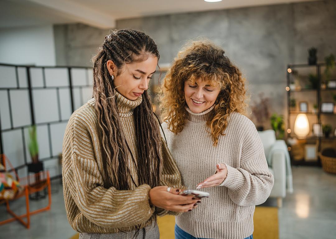 Two friends checking online and making digital payments from a smartphone.