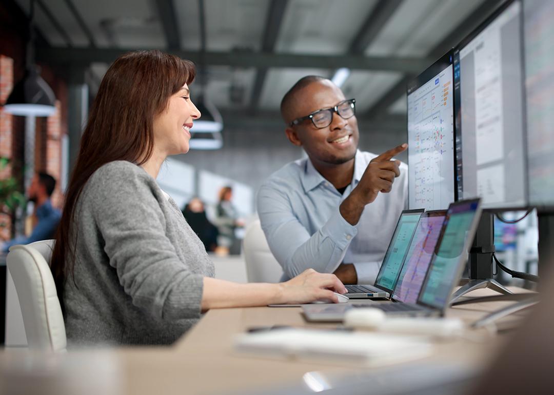 Two auditors carefully review financial data on a computer screen.