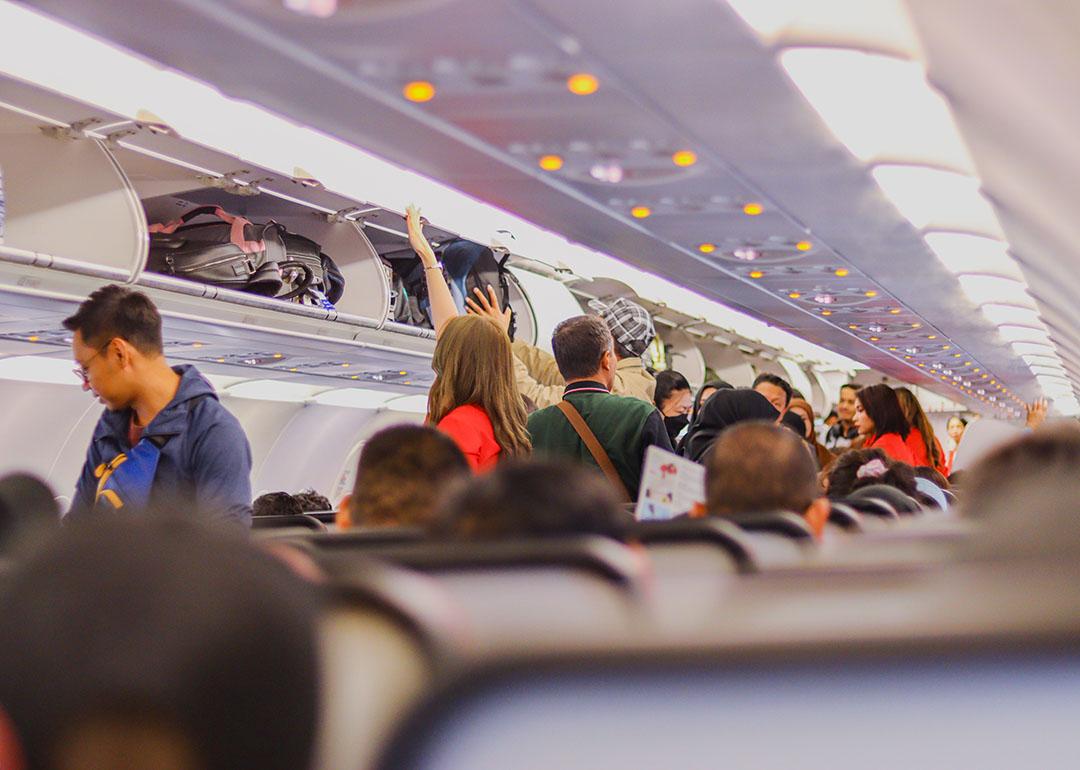 Passengers on a plane storing their carry-on luggage in the overhead compartments.