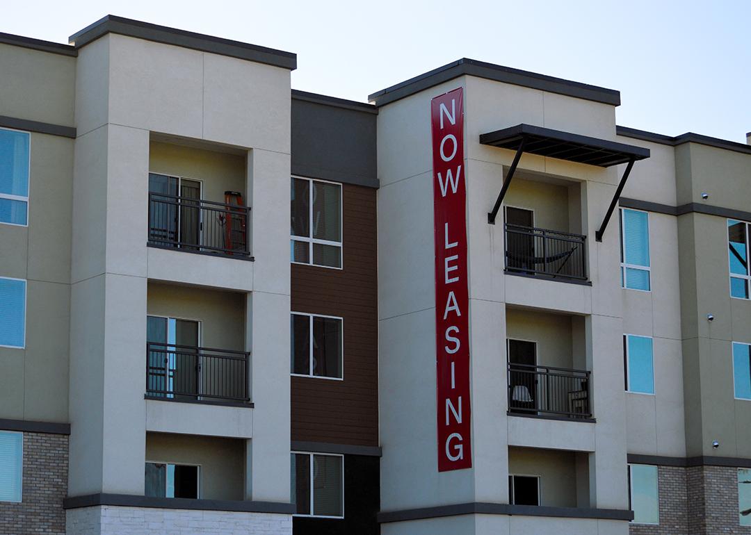 A modern apartment building with a huge 'now leasing' signage.