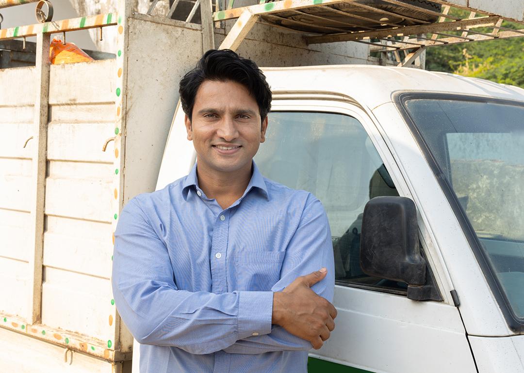 A driver posing for a photo next to a small truck after a delivery.