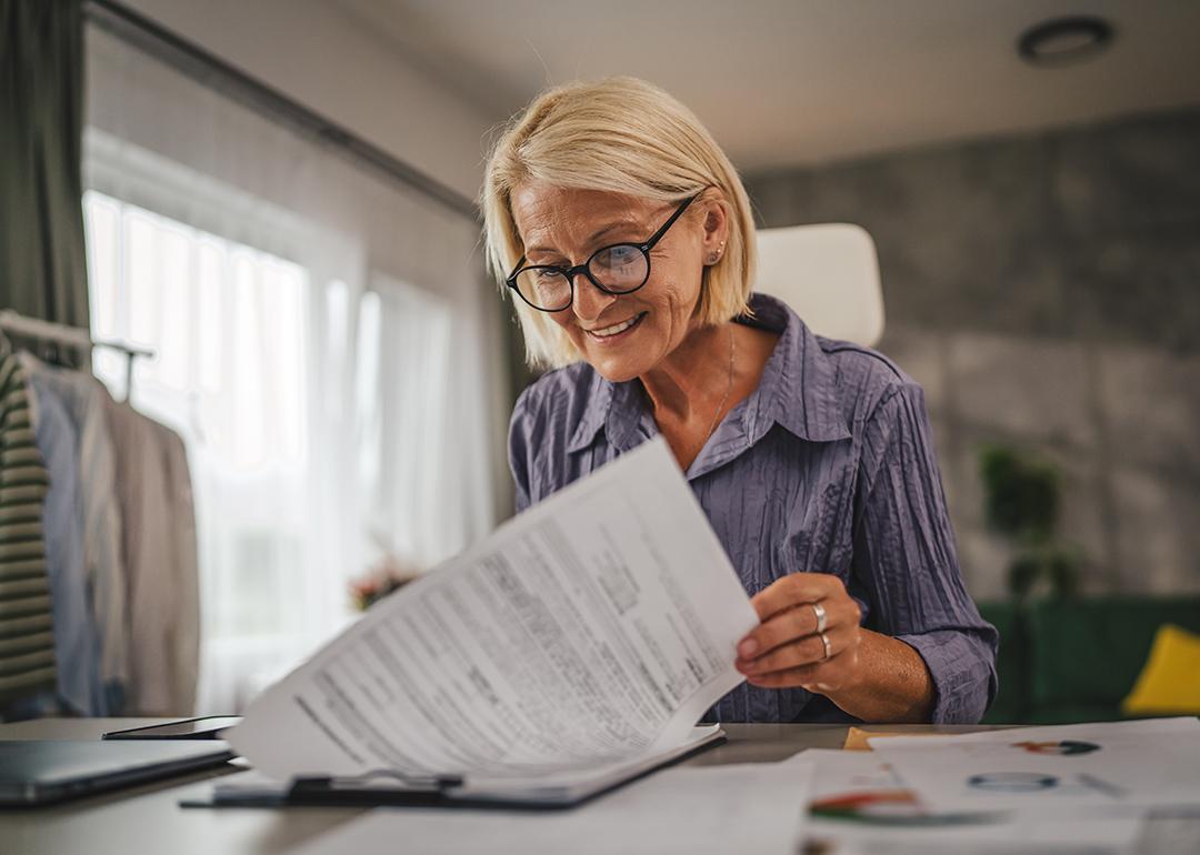 A middle-aged woman reviewing insurance documents at home.