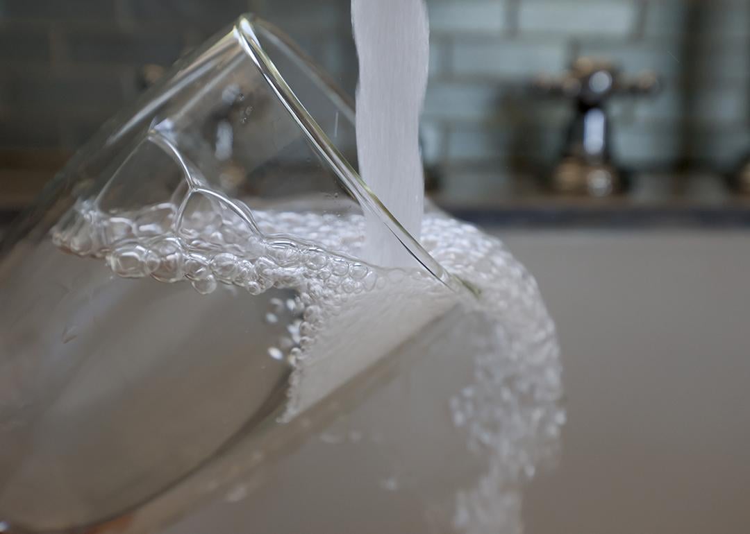 Water running from a kitchen faucet to fill a glass.