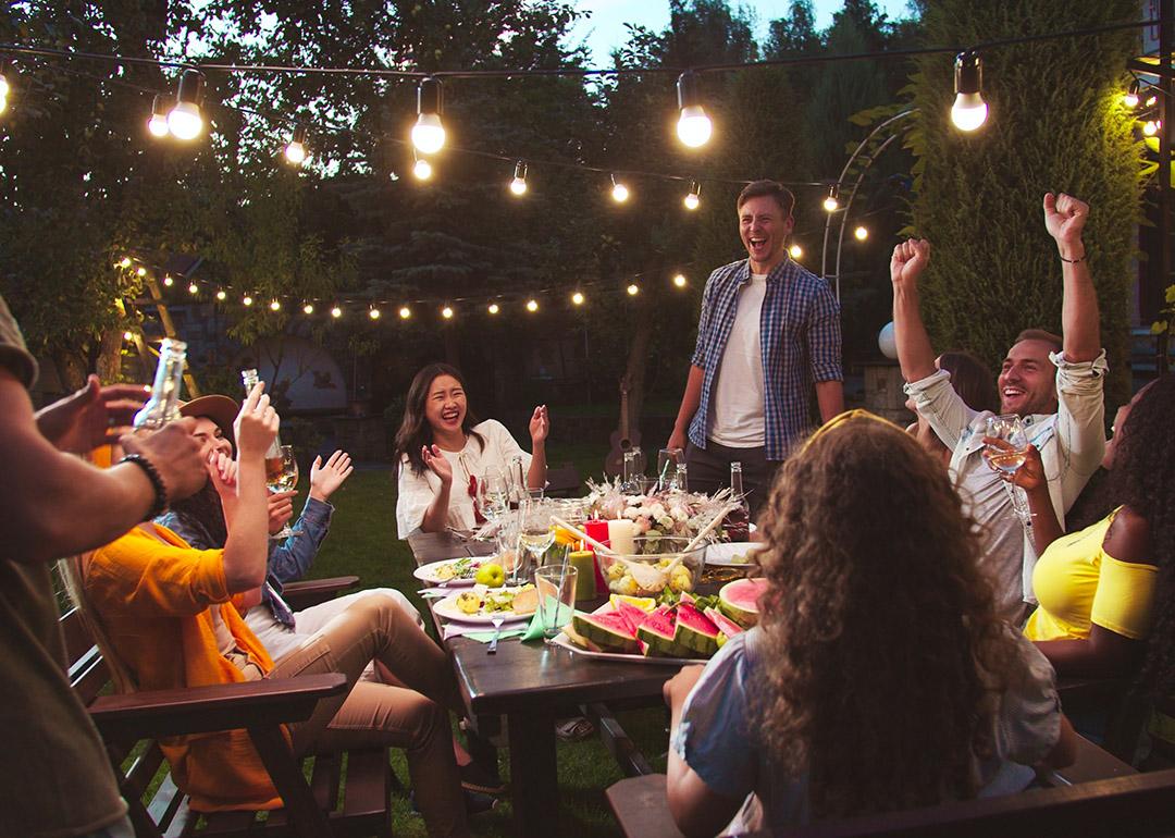 A group of friends laughing together and enjoying their time during a backyard party.